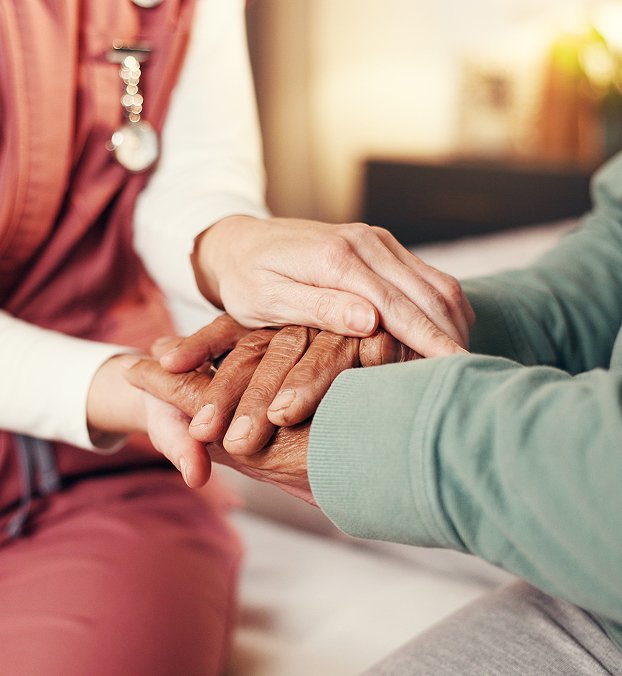Close-up of a carer holding an older person’s hand