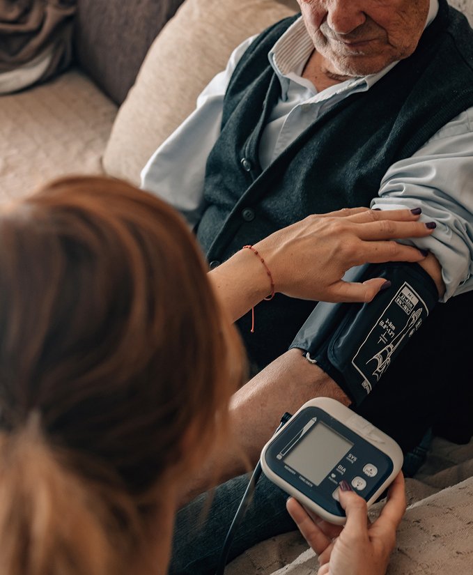 Nurse checking an older man’s blood pressure at home