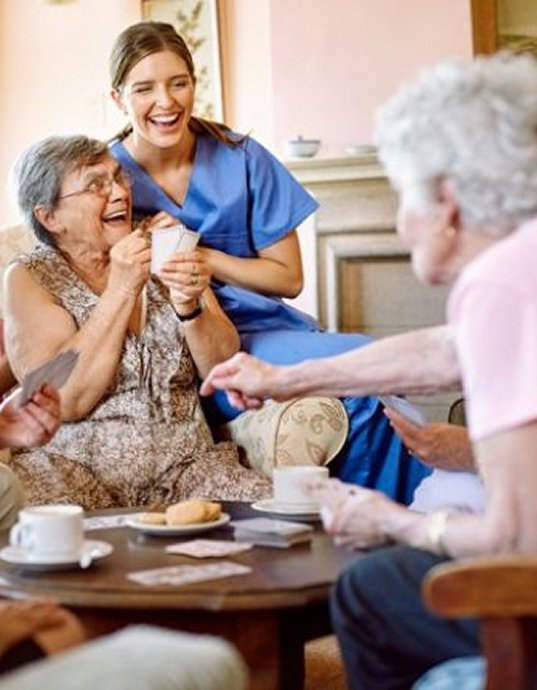 Carer laughing with older women over a cup of tea