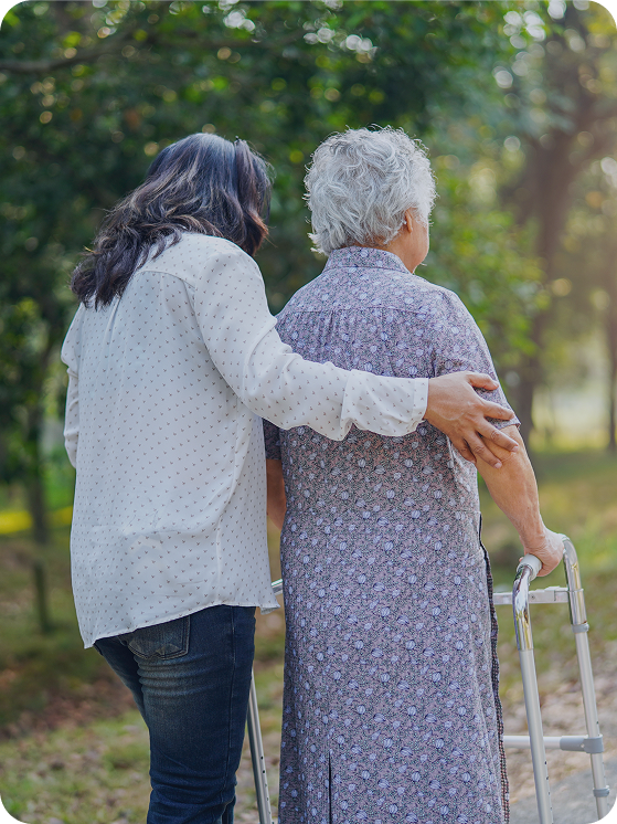 Support worker walking with an older woman using a walking frame