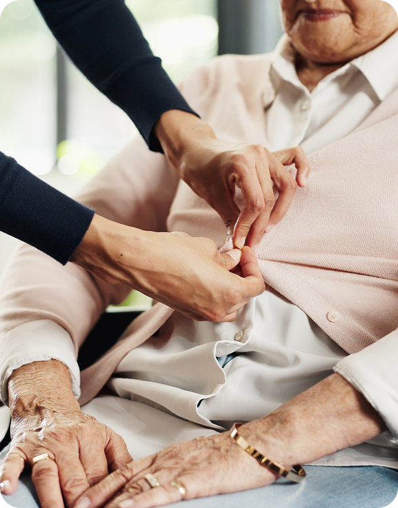 Carer’s hands helping an older person get dressed