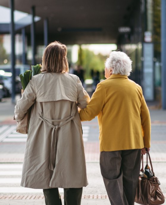 Support worker and older woman walking together through a shopping centre