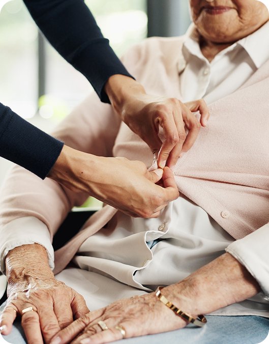 Carer helping an older person button their cardigan